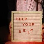 a person holding a sign that says help your self